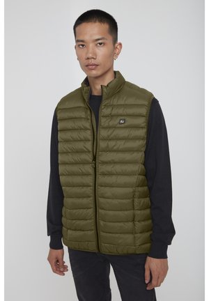 Olivengrøn puffer vest med lynlås foran, der har vandrette quiltede sektioner og et lille logo på brystet. Båret over en sort sweater.