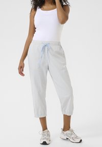 Vaaleansiniset ja valkoiset raidalliset lyhyet housut, joissa on joustava vyötärö, nyöri ja resorit, yhdistetty valkoisen hihattoman paidan ja tennareiden kanssa.