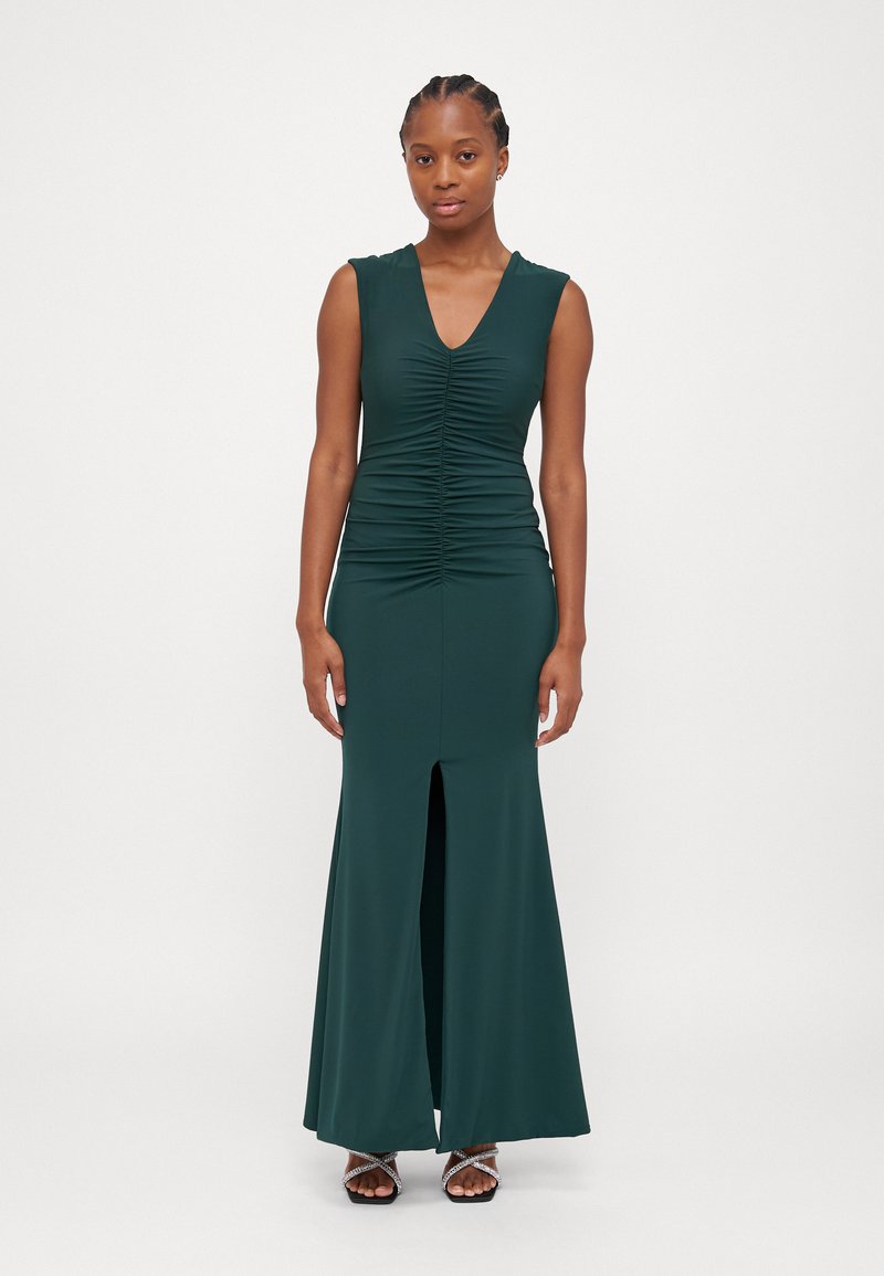 Green sleeveless dress with a V-neck, ruched bodice, and a front slit. Made from smooth fabric, it has a fitted silhouette and flared bottom.