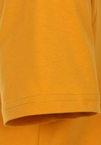 Sennepsgul bomulds T-shirt med korte ærmer, glat tekstur og lige kant med synlige syninger.