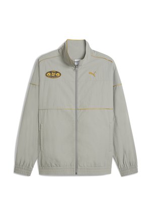 Veste zippée gris clair avec col montant, accents jaunes et logos brodés. Elle présente des poignets élastiques et deux poches avant.