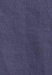 Gros plan sur la texture d'un tissu tissé violet foncé montrant des fils serrés et uniformes formant un motif en grille.