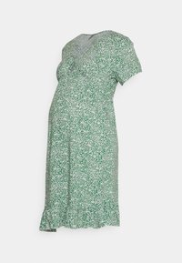 Vestido de maternidade feito de tecido leve, com um padrão floral verde e branco, mangas curtas, decote em V e uma bainha com babados.