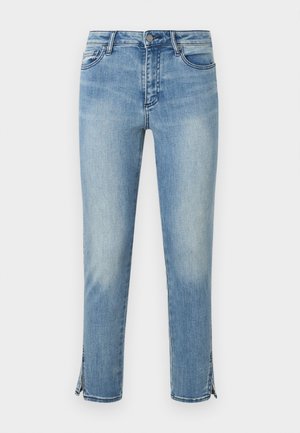 Φωτεινό μπλε ξεθωριασμένο τζιν με κουμπί μπροστά, τσέπες και σχισμές στους αστραγάλους και από τις δύο πλευρές, παρουσιάζεται πάνω σε άσπρο φόντο.