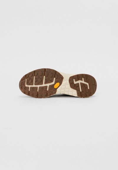 Semelle Vibram avec un motif en caoutchouc texturé marron ; semelle intermédiaire crème offrant un bon amorti. Conception légère et flexible adaptée à divers terrains.