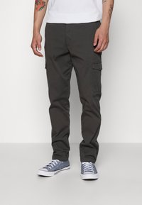 Cargo pants in dark gray fabric, featuring side pockets, a straight fit, and a smooth texture. Paired with blue sneakers.