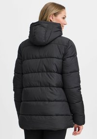 Svart pufferjacka med huva, med kviltad struktur, ribbade sömmar och en något böjd fåll. Minimalistisk design.