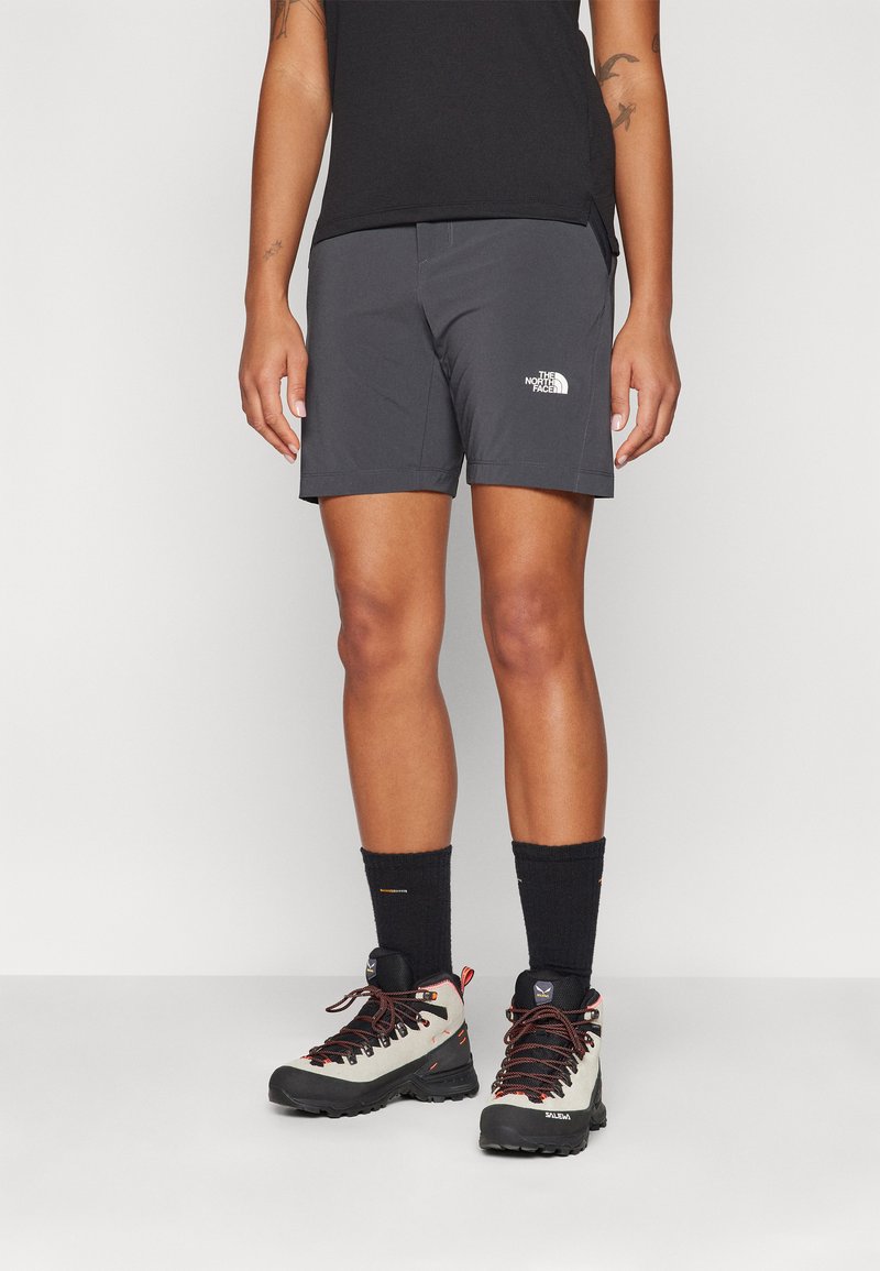 Grå shorts med en logotyp på framsidan, kombinerat med knästrumpor i svart och ljusa vandringsskor med svarta sulor och snören.