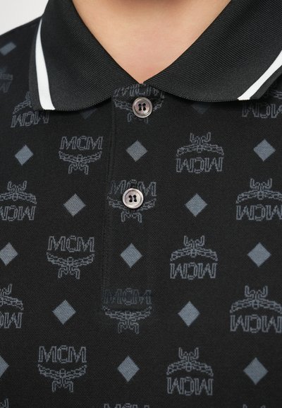Polo preta com tecido texturizado apresentando um padrão repetido do logótipo MCM e detalhes em diamante cinzentos, acabada com uma gola contrastante.
