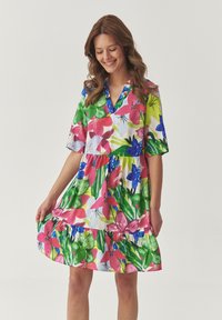 Bloemig jurk met levendige roze, groene en blauwe patronen. Korte mouwen, v-hals en gelaagde rimpelzoom. Gemaakt van lichtgewicht stof.