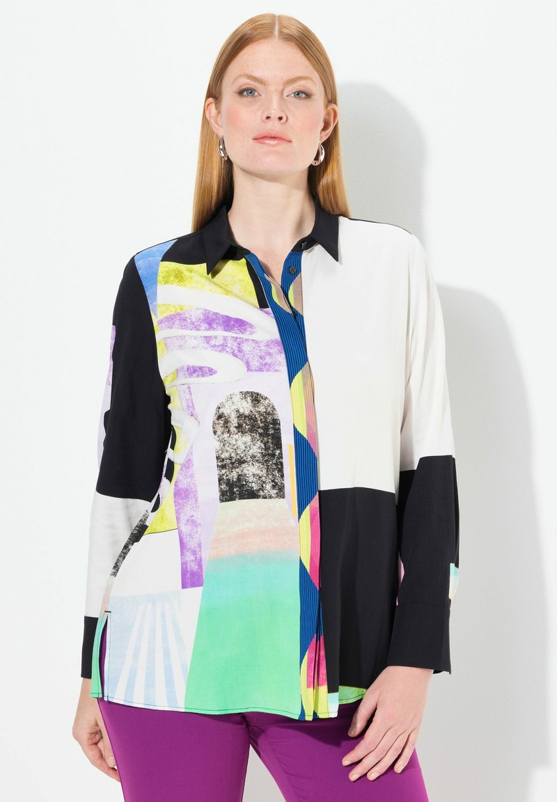 Chemise à boutons multicolore présentant des motifs géométriques, des sections contrastant le noir et le blanc, et une texture de tissu lisse.