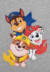 Tre cuccioli di cartone su uno sfondo grigio: uno indossa un cappello da poliziotto blu, un altro un cappello da pompiere rosso e il terzo un casco da costruzione giallo.