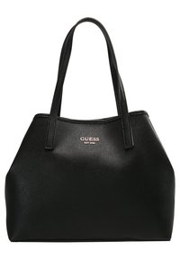 Sac fourre-tout en cuir noir texturé avec deux poignées et logo métallique "GUESS EST 1981" à l'avant.