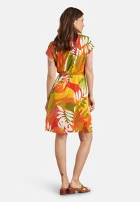 Korte mouw jurk in een levendig bloemenpatroon met groene, oranje en witte tinten; met een ceintuur in de taille en een lengte boven de knie.
