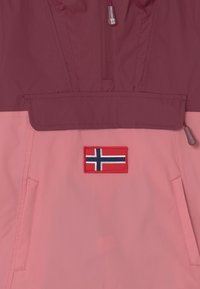 Pullover-Jacke aus zwei-farbigem Stoff; burgunderfarbenes Oberteil, pinke Unterseite. Mit norwegischem Flaggen-Patch, vorderer Reißverschlusstasche und verstellbarem Saum.