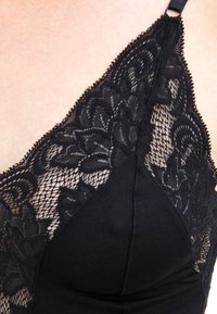 Zwart kanten bralette met bloemenpatronen, zachte stof, driehoekige cups, verstelbare bandjes en een gladde, effen onderzijde.