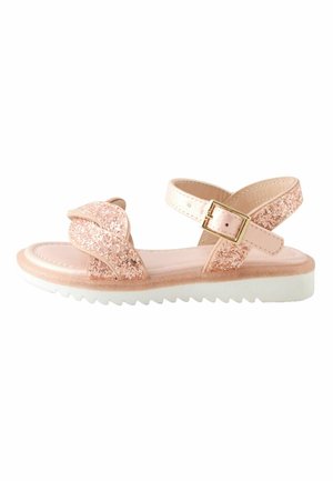 Glittery pink sandal with cross strap design, adjustable buckle, white sole, and textured tread for grip. Features shiny accents.
