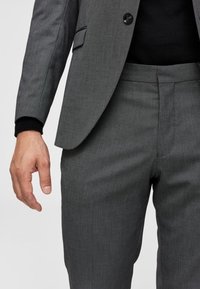 Gray suit with a textured fabric and tailored fit. Features a single button on the jacket and sleek, straight-leg trousers.