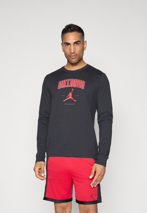 Schwarzes Langarm-T-Shirt mit rotem "CHICAGO"-Druck und Jordan-Logo, kombiniert mit roten Mesh-Shorts. Beide Teile haben ein sportliches Design.