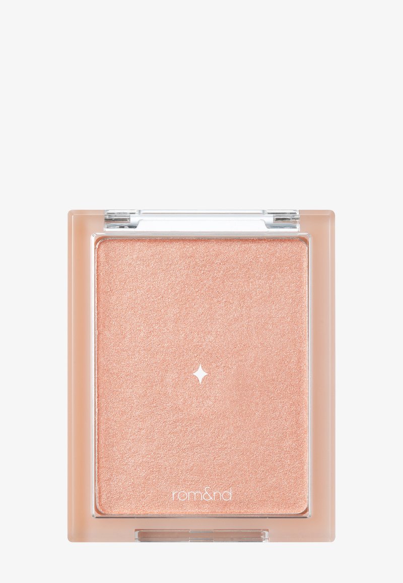 Presset highlighter i en klar firkantet kompakt. Har en glitrende ferskenfarge med en glatt tekstur og et lite stjernedesign i midten.