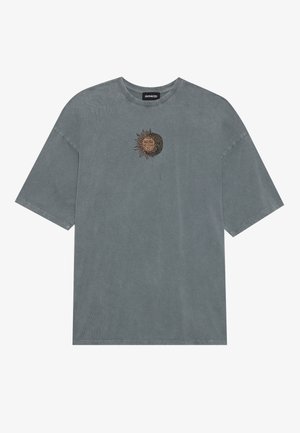 T-shirt in cotone grigio con vestibilità rilassata. Presenta un design ricamato di sole e luna in oro e nero sul petto. Maniche corte.