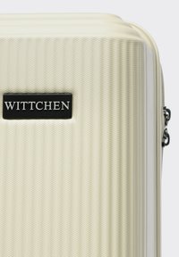 Harde koffer in een gestructureerde crèmekleurige afwerking met een prominent zwart "WITTCHEN" logo. Voorzien van een rits en stevige hardware accenten.