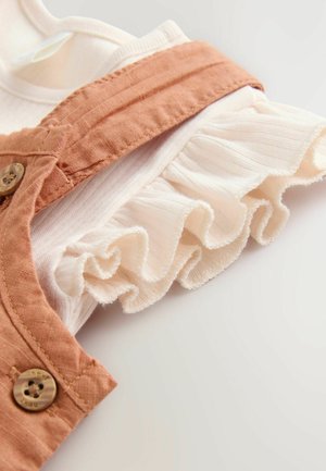 Set din bumbac format din două piese, cu bretele cu nasturi de culoare portocalie ruginită și un tiv alb cu volane. Material texturat și design moale, ușor.