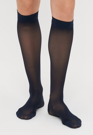 Marinblå knähöga strumpor i genomskinligt material med en slät yta och en kontrasterande, solid kant uppe, med en stängd tådesign.