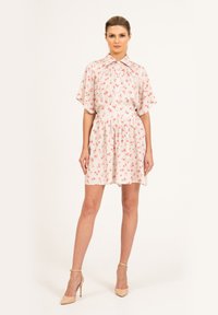 Kwiatowa sukienka wykonana z lekkiego materiału, z różowo-białym wzorem, krótkimi rękawami, kołnierzykiem na guziki i elastyczną talią.