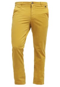 Chinos en coton jaune coupe slim, avec braguette zippée et fermeture par bouton, poches avant, et un détail logo discret sur la ceinture.
