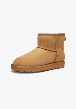 Short light brown suede ankle boot with flat sole and visible stitching, designed for casual wear.