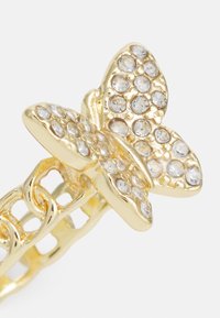 Anel de borboleta em ouro com uma banda texturizada, adornado com strass transparentes nas asas da borboleta, apresentando um delicado design de corrente.