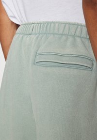 Ljust blå joggers med en strukturär väv, featuring en elastisk midja och en bakficka. Enkel och funktionell design.