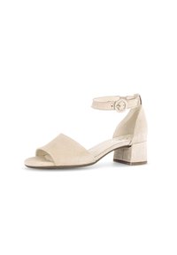 Beige Wildledersandalette mit einem breiten Vorderriemen, offener Zehenpartie, Knöchelriemen mit einer runden Schnalle und einem niedrigen, quadratisch geformten Blockabsatz.
