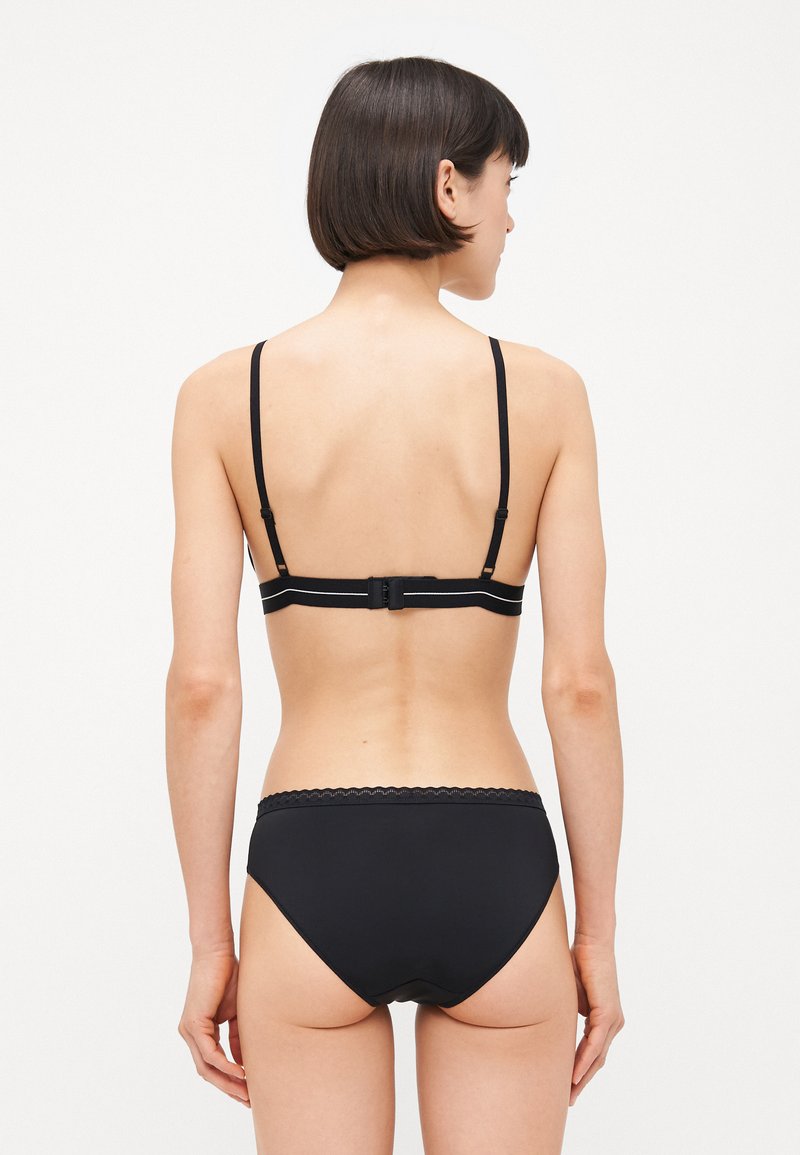 Conjunto de lencería negra con tirantes ajustables, cierre en la parte posterior y encaje en la cinturilla de las bragas, hecho de tela suave.