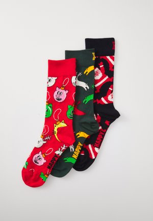 Trois paires de chaussettes en coton : rouges avec des motifs d'animaux, vert foncé avec des motifs festifs et noires avec un design de Père Noël ; toutes présentent des motifs colorés.