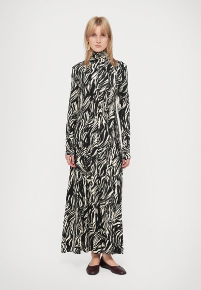 Sort og hvid langærmet kjole med zebra-lignende mønstre og høj krave. Stoffet ser glat og flydende ud og når anklerne.