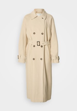 Beżowy trencz z dwurzędowym zapięciem, dużym kołnierzem i paskiem w talii. Posiada ozdobne guziki oraz profilowane rękawy z paskami.