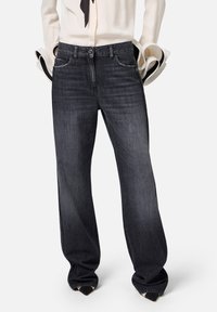 Jeans in denim scuro con taglio dritto, design a cinque tasche, dettagli di cucitura sottili e una finitura leggermente sbiadita all'altezza delle cosce.