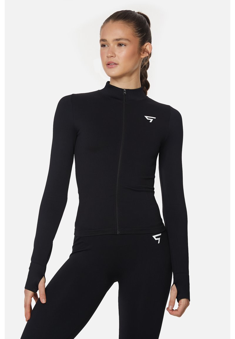 Schwarze sportliche Zip-up-Jacke aus glattem, dehnbarem Material. Mit langen Ärmeln mit Daumenlöchern und einem kleinen Logo auf der linken Brust.