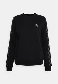 Svart sweatshirt med långa ärmar, featuring en rund halsringning, ribbade manschetter och en liten logotyp på bröstet. Armaccenter med återkommande design.