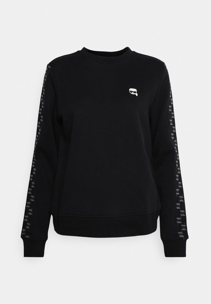 Svart sweatshirt med långa ärmar, featuring en rund halsringning, ribbade manschetter och en liten logotyp på bröstet. Armaccenter med återkommande design.