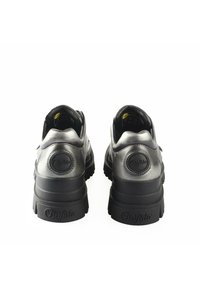 Zapatillas negras metálicas con punta redondeada, cuello acolchado y suela de goma texturizada. Presentan un logotipo en el talón y un acabado elegante y suave.