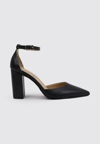 Zapato de tacón alto de cuero negro con punta afilada, correa en el tobillo y tacón ancho. Textura suave y diseño sencillo.