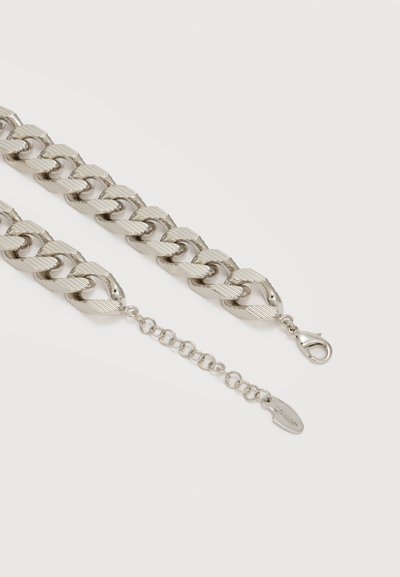 Κολιέ με παχιά αλυσίδα σε ασημί τόνο, με υφασμένους κρίκους και ρυθμιζόμενο κούμπωμα που φέρει προσαρτημένη οβάλ ετικέτα.