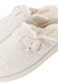 Zapatillas de casa de un suave color beige claro, hechas de fieltro suave con forro de pelaje sintético, cuentan con una hebilla decorativa y una suela de goma para mayor tracción.