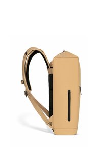 Mochila impermeable color beige con un diseño estructurado y rectangular, detalles en negro, parte superior plana y un bolsillo lateral con cremallera. Correas ajustables.