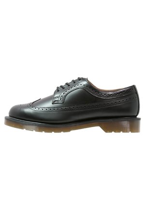 Czarny skórzany but brogue z wzorem typu wingtip, perforowanymi detalami, czarnymi sznurowadłami oraz grubą, półprzezroczystą, brązową gumową podeszwą.