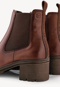 Bottes courtes en cuir marron avec panneaux latéraux élastiques, languettes de traction et talons blocs empilés.
