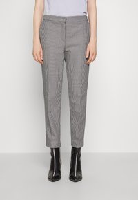 Skräddarsydda rutiga byxor i svart och vitt, med smal passform, cropped längd och sidofickor, i kombination med eleganta svarta ankelstövlar.